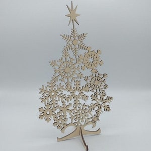 May include: A wooden Christmas tree ornament made of snowflakes. The tree is freestanding and has a star on top.