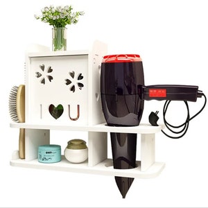May include: White wall-mounted shelf with two shelves and a compartment with a cut-out design that says "I love you". The shelf has a hairdryer, hairbrush, and two containers on it.