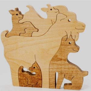 Könnte beinhalten: Ein Holzpuzzle mit vier aufwendig geschnitzten Ziegen, die jeweils ineinander verschachtelt sind. Die Ziegen sind aus hellem braunem Holz mit natürlicher Maserung gefertigt.