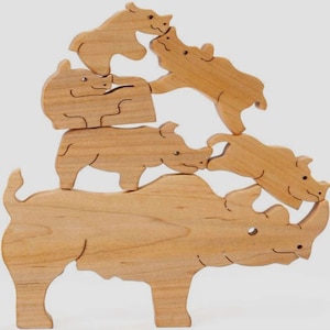 May include: A wooden stacking toy featuring five rhinoceroses of varying sizes. The rhinoceroses are all made of natural wood and have a smooth, polished finish. The toy is designed to be stacked on top of each other, with the largest rhinoceros at the bottom and the smallest at the top.