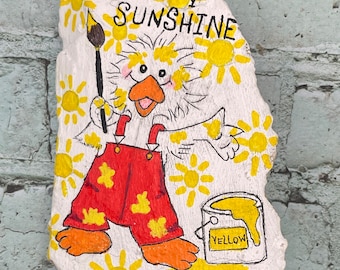 Dibujo de pato pintando soles amarillos, "Eres mi sol", roca pintada, arte de piedra pintada