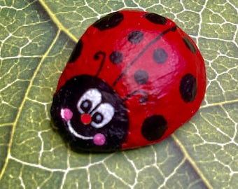 黒い点のあるかわいい赤いてんとう虫、ペイントされた岩、石の絵