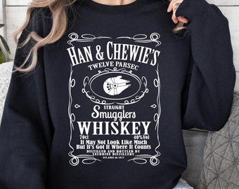 May include: Black sweatshirt with a white graphic of a whiskey label that says "Han & Chewie's Twelve Parsec Straight Smugglers Whiskey 70cl 40%Vol It May Not Look Like Much But It's Got It Where It Counts Distilled and Bottled by"