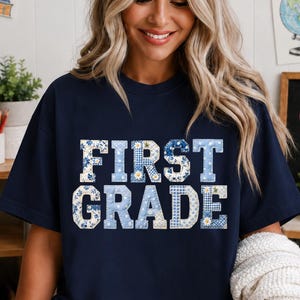 Peut inclure: Un t-shirt bleu marine à manches courtes avec le texte FIRST GRADE écrit en lettres capitales. Les lettres sont remplies d'un motif bleu clair et blanc composé de petites fleurs et d'un motif à carreaux vichy classique sur le tissu.