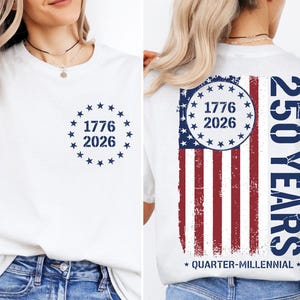 a white t-shirt with a graphic design on the back, depicting the year 1776 and the year 2026 within a circular design, along with an American flag pattern. The text on the t-shirt reads "1776 2026" and "250 YEARS" in a vertical orientation.