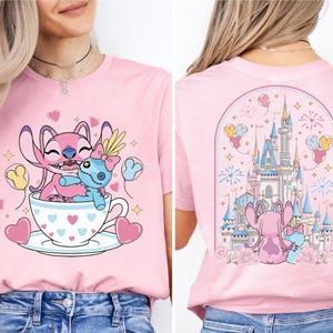 A woman wearing a pink t-shirt with a cartoon image of Stitch and a cup of tea, along with a castle and fireworks in the background.