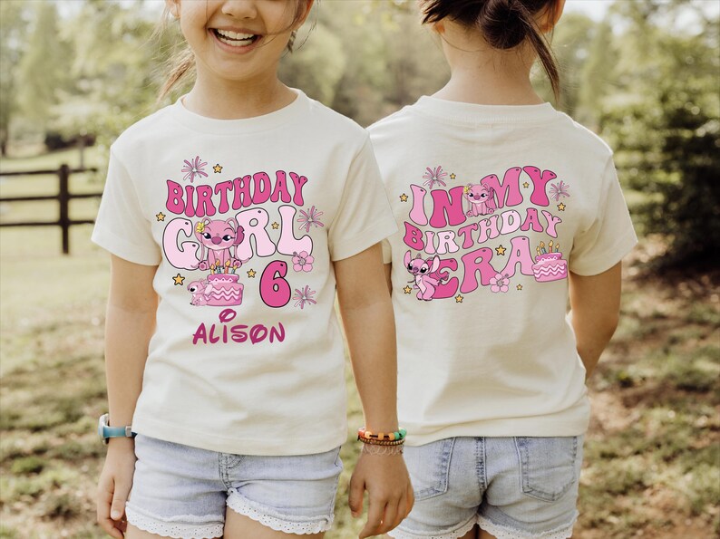 A young girl wearing a white t-shirt with a birthday design and text on the back.