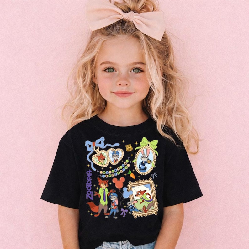 A young girl with blonde hair wearing a black t-shirt with colorful cartoon characters and designs.