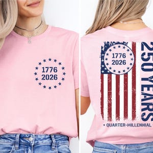 A woman wearing a pink t-shirt with a graphic design on the back. The design features the numbers 1776 and 2026, along with an American flag pattern, and the text "250 YEARS" and "QUARTER-MILLENNIAL".
