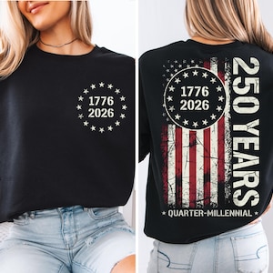a woman wearing a black t-shirt with a graphic design on the back. The design includes a circle with the numbers 1776 and 2026, and an American flag pattern. The text on the t-shirt reads "250 YEARS" and "QUARTER-MILLENNIAL".
