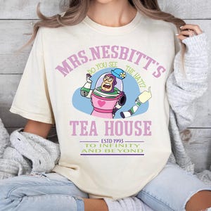 a woman wearing a t - shirt that says mrs nestt's tea house