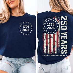 A woman wearing a navy blue sweatshirt with a graphic design on the back. The design features a combination of stars and stripes, along with the text "1776", "2026", and "250 YEARS" printed on it.
