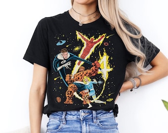 May include: Black t-shirt with a vibrant comic book illustration of the Fantastic Four in a space setting. The design includes the Human Torch, Mr. Fantastic, The Thing, and Invisible Woman. The shirt is made of a soft material.