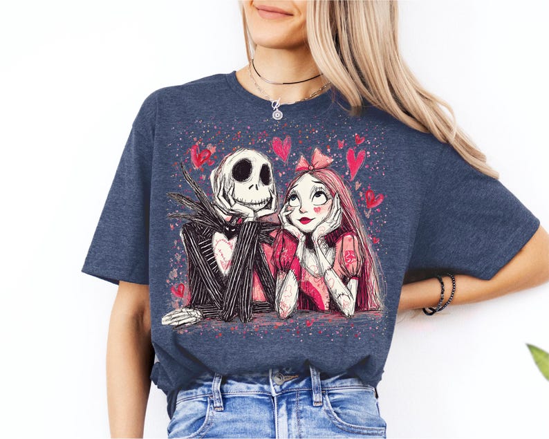 A woman wearing a blue t-shirt with a graphic design featuring a skeleton and a woman with a heart-shaped headband.