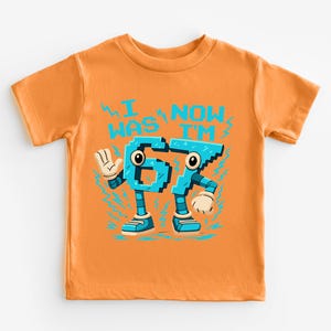 An orange t-shirt with a graphic design featuring a character made up of the number 6, with the text "I WAS NAMED 65" printed on it.