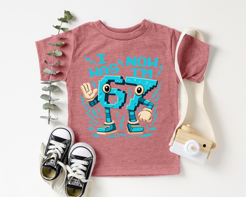 A pink t-shirt with a graphic design featuring a character made up of numbers, along with a pair of sneakers and a camera.
