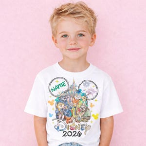 A young boy wearing a white t-shirt with a Disney-themed graphic and text, including the Disney logo and the text "Disney 2020".