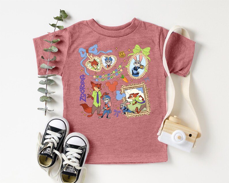 a pink t-shirt with a cartoon character design, a pair of black and white sneakers, and a small wooden camera.