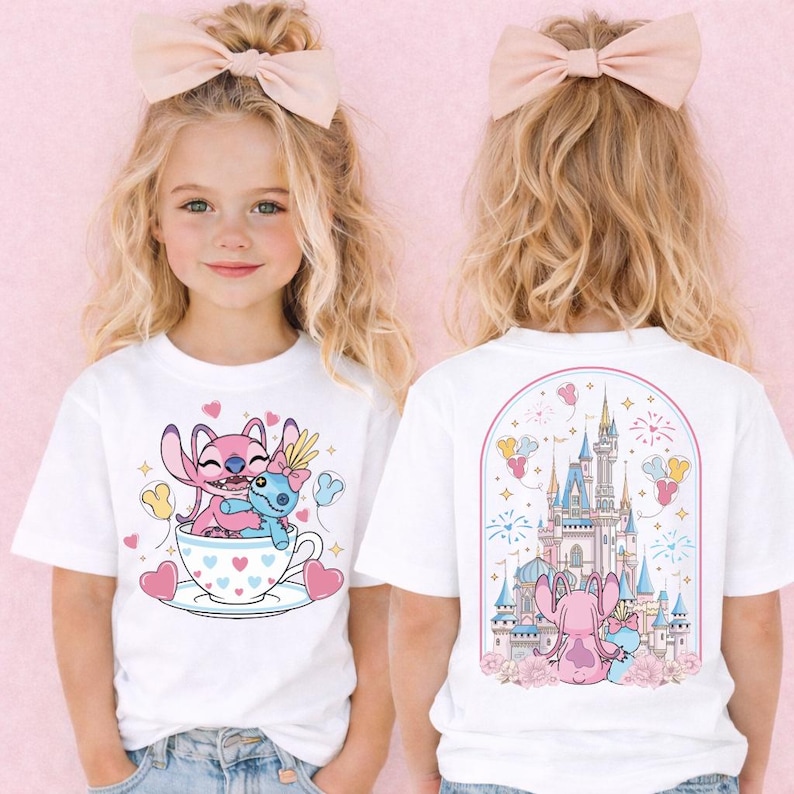 A young girl with blonde hair wearing a white t-shirt with a cartoon image of a cup with a cartoon character inside.