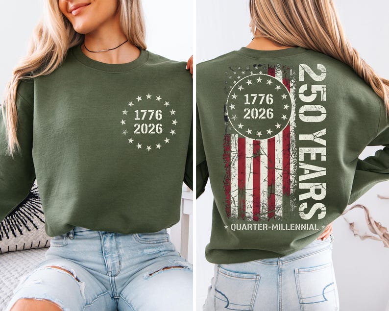 A woman wearing a green sweatshirt with a graphic design on the back. The design features a circle with the numbers 1776 and 2026, and an American flag pattern.