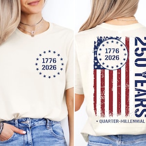 a woman wearing a white t-shirt with a graphic design on the back. The design includes a circle with the numbers 1776 and 2026, and an American flag pattern. The text on the t-shirt reads "1776 2026" and "250 YEARS" along with "QUARTER-MILLENNIAL".