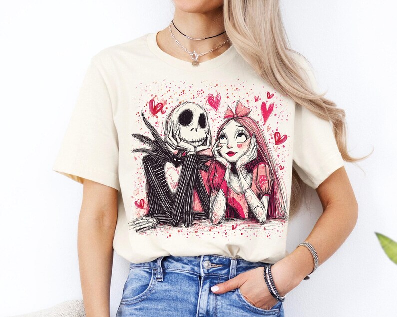 A woman wearing a white t-shirt with a graphic design featuring a skeleton and a woman with a pink bow.