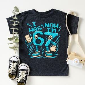 a black t-shirt with a graphic design, a pair of black and white sneakers, and a white camera.