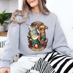 a woman wearing a sweatshirt with a picture of a fairy on it