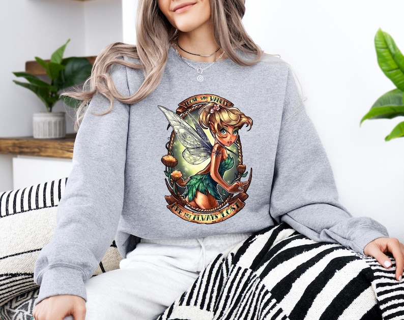a woman wearing a sweatshirt with a picture of a fairy on it