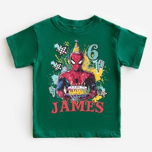 A green t-shirt with a Spider-Man graphic and the number 6, along with the text "JAMES" printed on it.