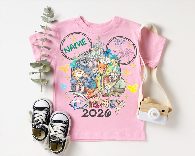 A pink Disney-themed t-shirt with a group of cartoon characters, including Mickey Mouse, Donald Duck, Goofy, and others, along with a pair of sneakers and a camera.