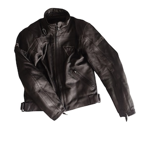 Może przedstawiać: Czarna sk&oacute;rzana kurtka motocyklowa z wysokim kołnierzem, zapięciem na zamek błyskawiczny i wieloma kieszeniami. Kurtka ma nazwę marki "DAINESE" na rękawach i logo na piersi. Posiada regulowane paski w talii.