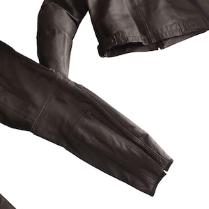 Może przedstawiać: Ciemnobrązowa sk&oacute;rzana kurtka z zapięciem na zamek błyskawiczny i perforowanymi detalami na rękawach. Kurtka ma klasyczny kr&oacute;j z dopasowanym krojem, odpowiednia na r&oacute;żne okazje.