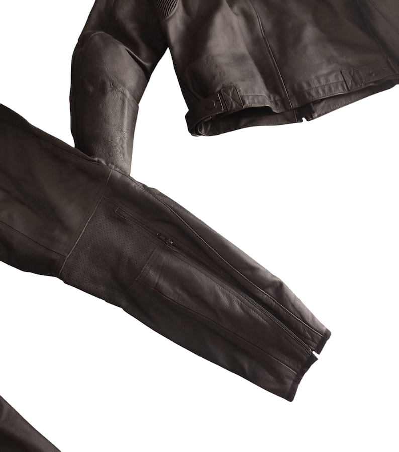 Może przedstawiać: Ciemnobrązowa sk&oacute;rzana kurtka z zapięciem na zamek błyskawiczny i perforowanymi detalami na rękawach. Kurtka ma klasyczny kr&oacute;j z dopasowanym krojem, odpowiednia na r&oacute;żne okazje.