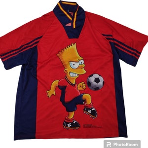 May include: Red and navy blue soccer jersey featuring Bart Simpson kicking a soccer ball. The jersey has a V-neck collar with yellow and red trim, and navy blue stripes on the sleeves. The jersey has a cartoon graphic of Bart Simpson.