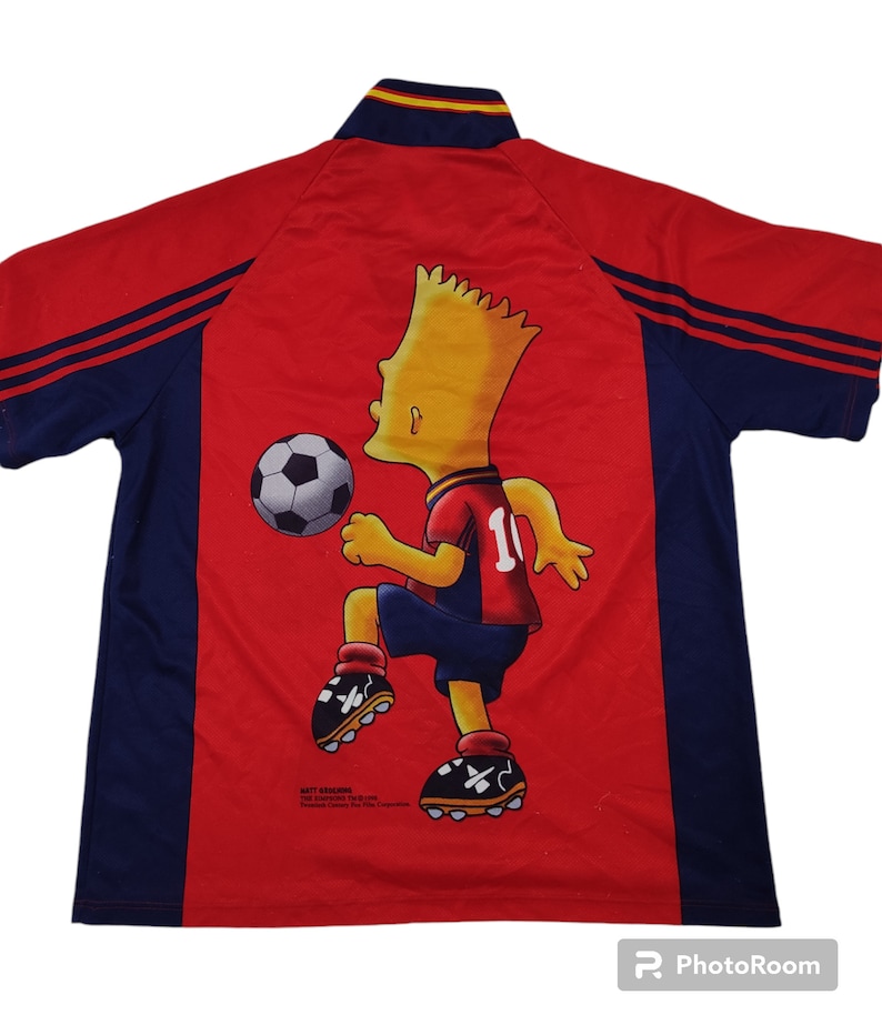 May include: Red and navy blue soccer jersey featuring Bart Simpson kicking a soccer ball. The jersey has a collar with yellow and red stripes and the number 10 on the back. The jersey is a vintage item.