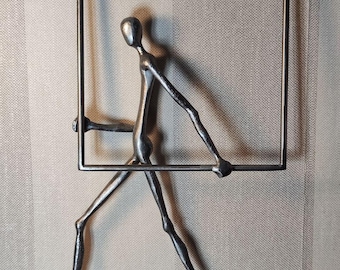 MetalSculpture, AbstractFigure, MinimalistDesign, WalkingMan, ArtisticExpression, BreakingBoundaries, ContemporarySculpture, SquareFrame