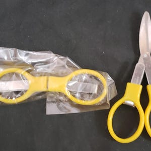 May include: Two pairs of yellow handled scissors with silver blades. One pair is closed and the other is open.