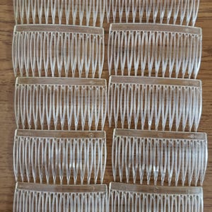 May include: Set of six clear plastic hair combs. Each comb has a row of small teeth and a curved shape.