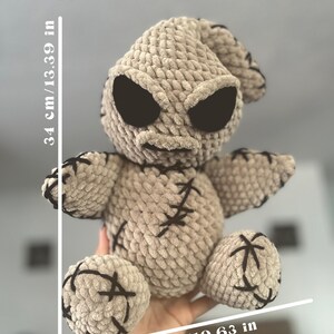 K&ouml;nnte beinhalten: Ein geh&auml;keltes Pl&uuml;schtier, das einem Charakter aus dem Film "Nightmare Before Christmas" &auml;hnelt. Das Spielzeug ist beige mit schwarzen N&auml;hten und hat gro&szlig;e schwarze Augen. Das Spielzeug ist 34 cm hoch und 27 cm breit.