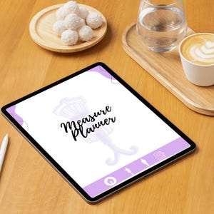 Puede incluir: Una tableta digital que muestra un diseño de "Measure Planner" con una ilustración de maniquí. La tableta está sobre una superficie de madera, acompañada de un lápiz óptico blanco, una taza de café, un vaso de agua y un plato de confitería blanca.