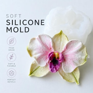 May include: A white silicone mould and a detailed orchid flower. The orchid has pink and yellow petals with a purple centre. The image text reads "SOFT SILICONE MOLD", "FOOD GRADE", "SOFT & FLEXIBLE", and "PERFECT DETAILS".