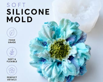 Pode incluir: Um molde de silicone translúcido e uma flor moldada com pétalas azuis, brancas e verdes. O texto diz: SOFT SILICONE MOLD, FOOD GRADE, SOFT & FLEXIBLE, PERFECT DETAILS. A flor tem um centro verde texturizado e pétalas em camadas e franzidas.