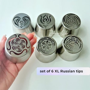 May include: A white ceramic mug with a black handle and the text "But First, Coffee" in a bold, black font. The mug is set against a blurred background, suggesting a cozy setting.