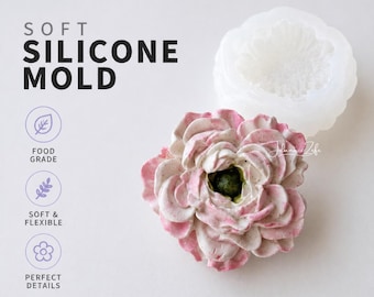 Pode incluir: Um molde de silicone macio com um design floral. O molde é branco e apresenta o texto "SOFT SILICONE MOLD", "FOOD GRADE", "SOFT & FLEXIBLE" e "PERFECT DETAILS". Uma flor acabada em rosa e branco está ao lado do molde.