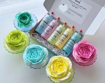 May include: A box set of USFA Neon Palette dry spray color system with six bottles in various colors, including blue, pink, and yellow. The set is accompanied by several decorative, colorful, and edible flower-shaped decorations.