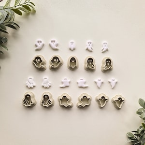 May include: A set of 20 white and beige plastic ghost cookie cutters. The cutters are arranged in rows on a white background.