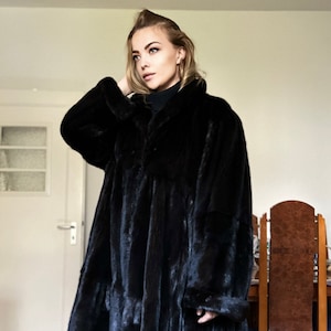 Peut inclure: Un long manteau en fourrure noire avec un col montant. Le manteau est fait d'une fourrure douce et luxueuse et a un style classique et élégant.