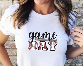 May include: White t-shirt with the text "game day" in black lettering. The "D" in "day" is a baseball with red stitching. A brown baseball bat is above the text.