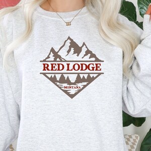 May include: A gray sweatshirt with a brown mountain graphic and the text "RED LODGE - MONTANA" in red.
